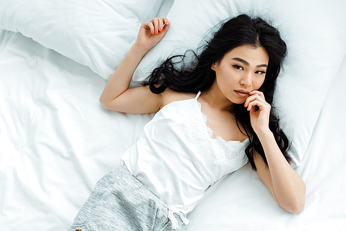 overhead view of attractive thai woman  while lying in bedroom