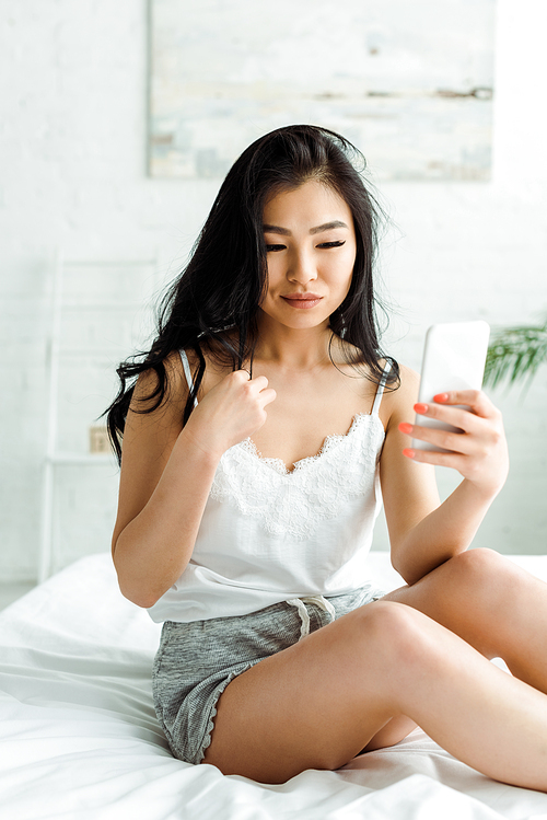 selective focus of pretty asian girl using smartphone in bedroom