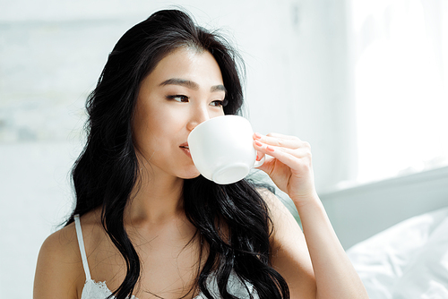 attractive brunette thai woman drinking tea at home