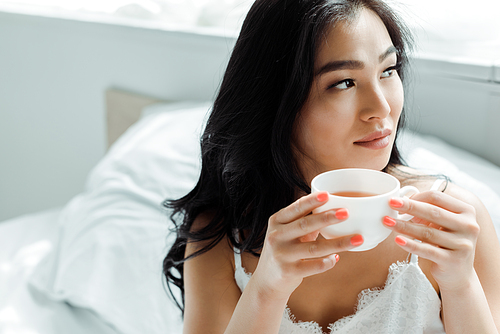 selective focus of pretty thai woman holding cup with tea