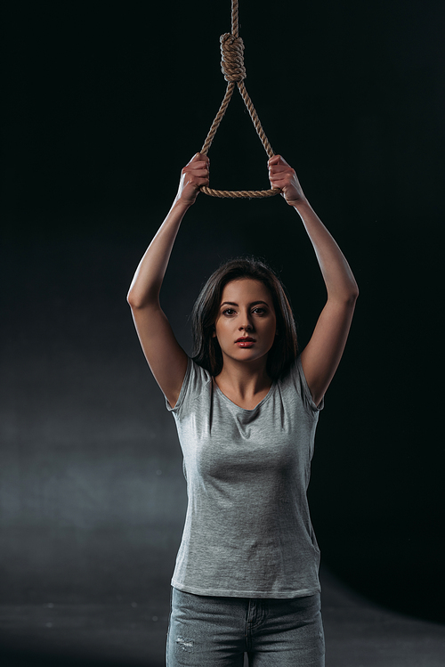depressed young woman going to commit suicide while holding hanging rope noose and  on black background