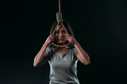 depressed young woman going to commit suicide while holding hanging rope loop and  isolated on black