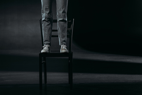 cropped view of self-destroyer standing on chair and going to commit suicide on black background