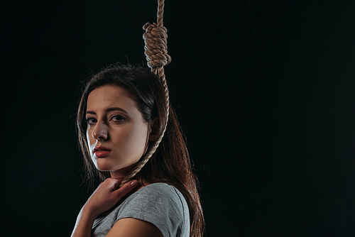 frustrated young woman  while standing with noose on neck isolated on black