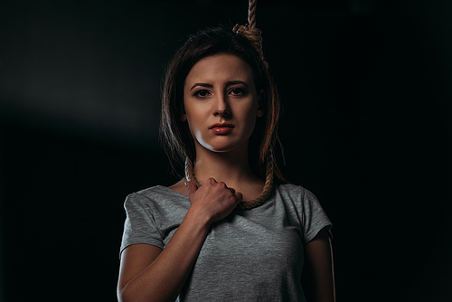 frustrated woman  while standing with noose on neck on black background
