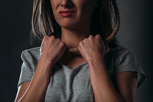 cropped view of depressed, crying woman putting noose on neck on black background