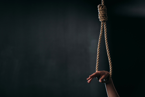 cropped view of female hand in hanging rope noose on black background