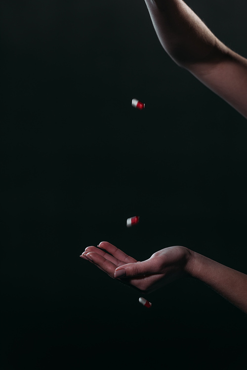 cropped view of woman throwing pills in open hand while going to commit suicide isolated on black