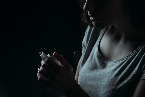 cropped view of woman going to commit suicide and holding container with pills isolated on black