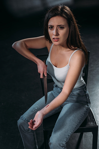 hopeless young woman  while committing suicide by cutting veins with knife on dark background