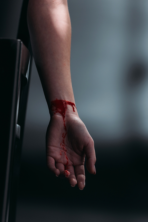 cropped view of female hand with bleeding cut veins on dark background