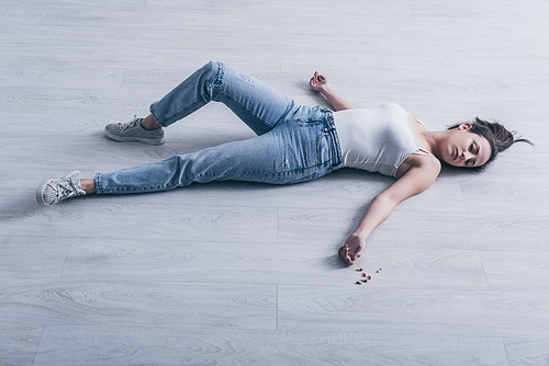 unconscious woman, committed suicide by overdosing medicines, lying on floor near scattered pills
