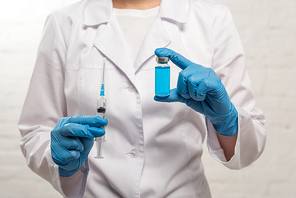 Cropped view of doctor holding syringe and jar of vaccine on white background
