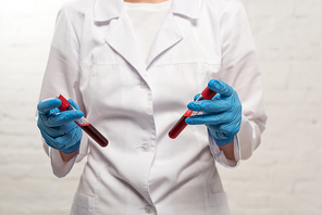 Cropped view of doctor holding test tubes with blood samples on white background