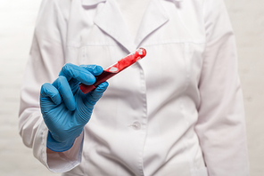 Selective focus of doctor holding test tube with blood sample on white background