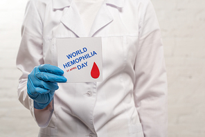 Cropped view of doctor holding card with world hemophilia day on white background