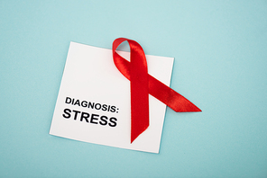 Top view of card with stress diagnosis and red ribbon isolated on blue