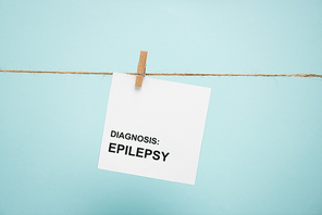 Card with diagnosis epilepsy lettering on rope with pin isolated on blue
