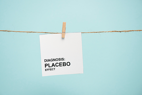 Card with diagnosis placebo effect lettering on rope with pin isolated on blue