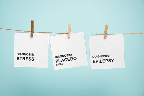 Cards with stress, placebo effect and epilepsy diagnoses lettering on rope with pins isolated on blue