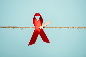 Pin with aids awareness red ribbon on rope isolated on blue