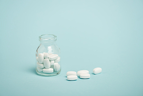 Jar with pills on blue surface with copy space
