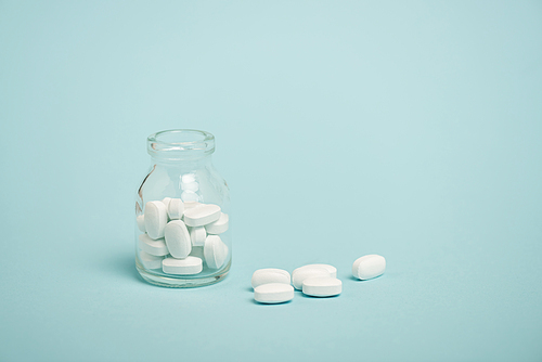 Jar with pills on blue surface with copy space