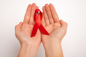Cropped view of woman holding red ribbon of aids awareness on white background