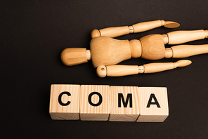 High angle view of blocks with coma lettering and wooden doll isolated on black