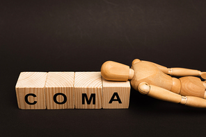 Wooden doll on cubes with coma lettering isolated on black