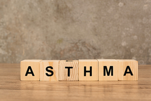 Wooden cubes with asthma lettering on wooden table on grey background