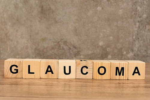 Glaucoma lettering on cubes on wooden table on grey background
