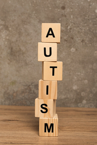 Stacked blocks with autism lettering on wooden table on textured grey background