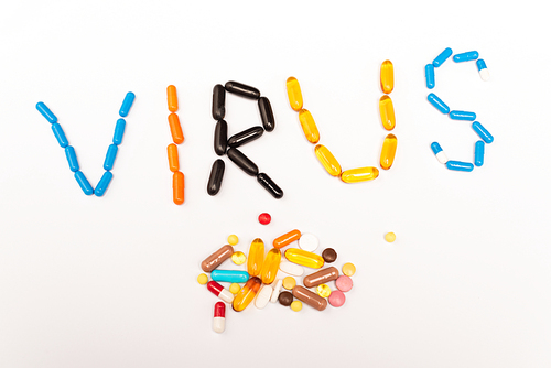Top view of virus lettering and pile of pills on white background