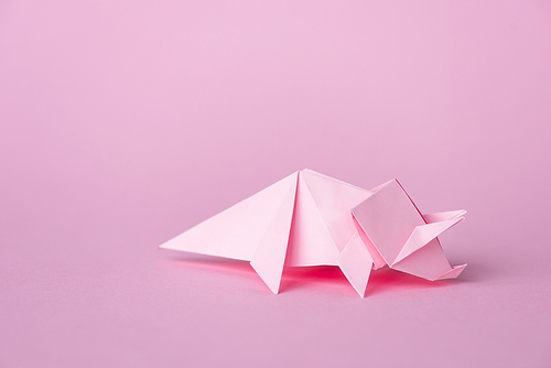 small origami rhinoceros on pink with copy space
