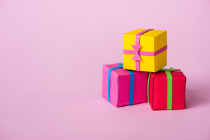 small colorful paper presents on pink with copy space