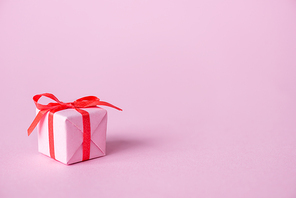 small paper gift with ribbon and bow on pink