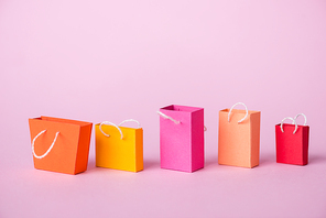 colorful and small shopping bags on pink with copy space