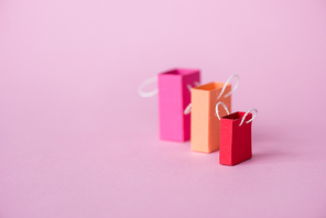 selective focus of small shopping bags on pink with copy space