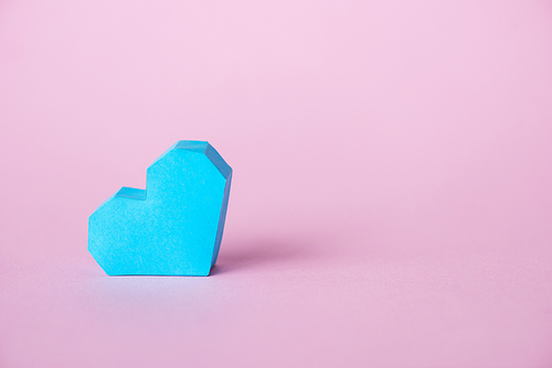blue origami heart on pink with copy space