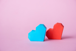 red and blue origami hearts on pink with copy space