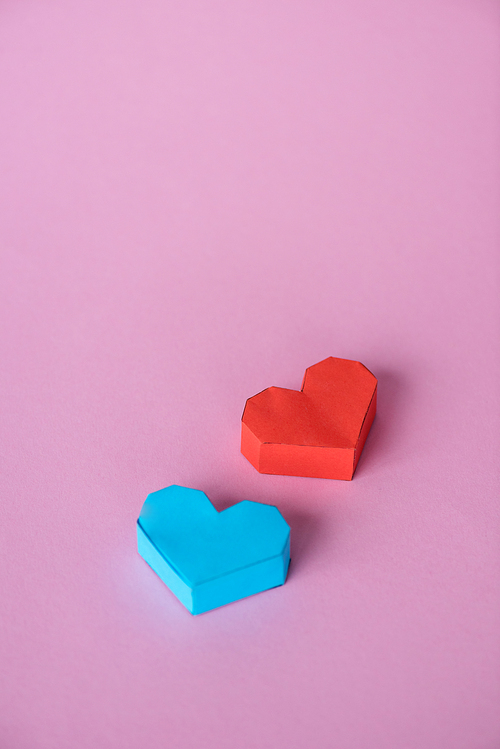 blue and red origami hearts on pink with copy space