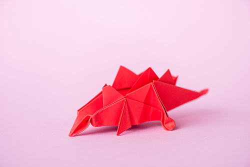 red origami dinosaur on pink with copy space