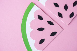 top view of sliced paper watermelon with black seeds isolated on pink