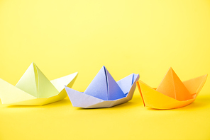 colorful paper ships on yellow with copy space