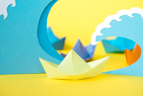 selective focus of paper ship near waves on yellow