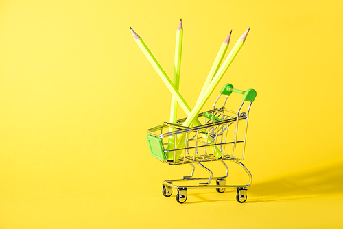 toy shopping cart with pencils on yellow