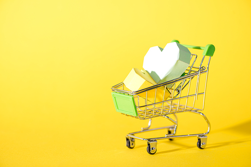 origami hearts in toy shopping cart on yellow