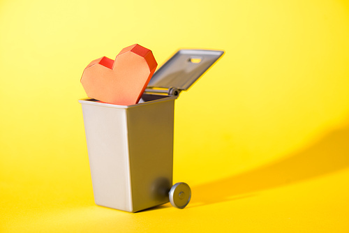 paper heart in small trash can on yellow