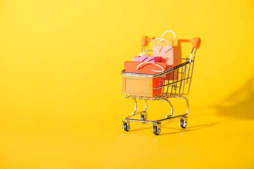 small shopping bags in toy shopping cart on yellow